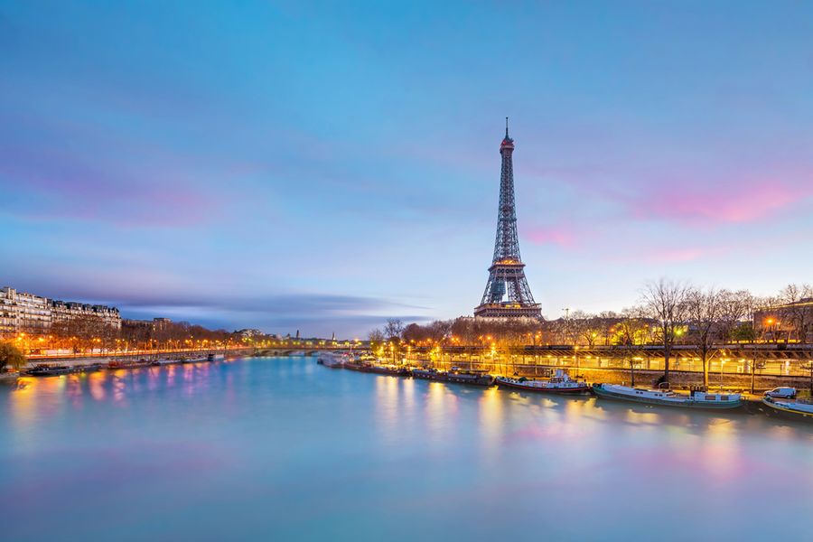 Een foto van de Eiffeltoren, genomen over de rivier bij schemering.